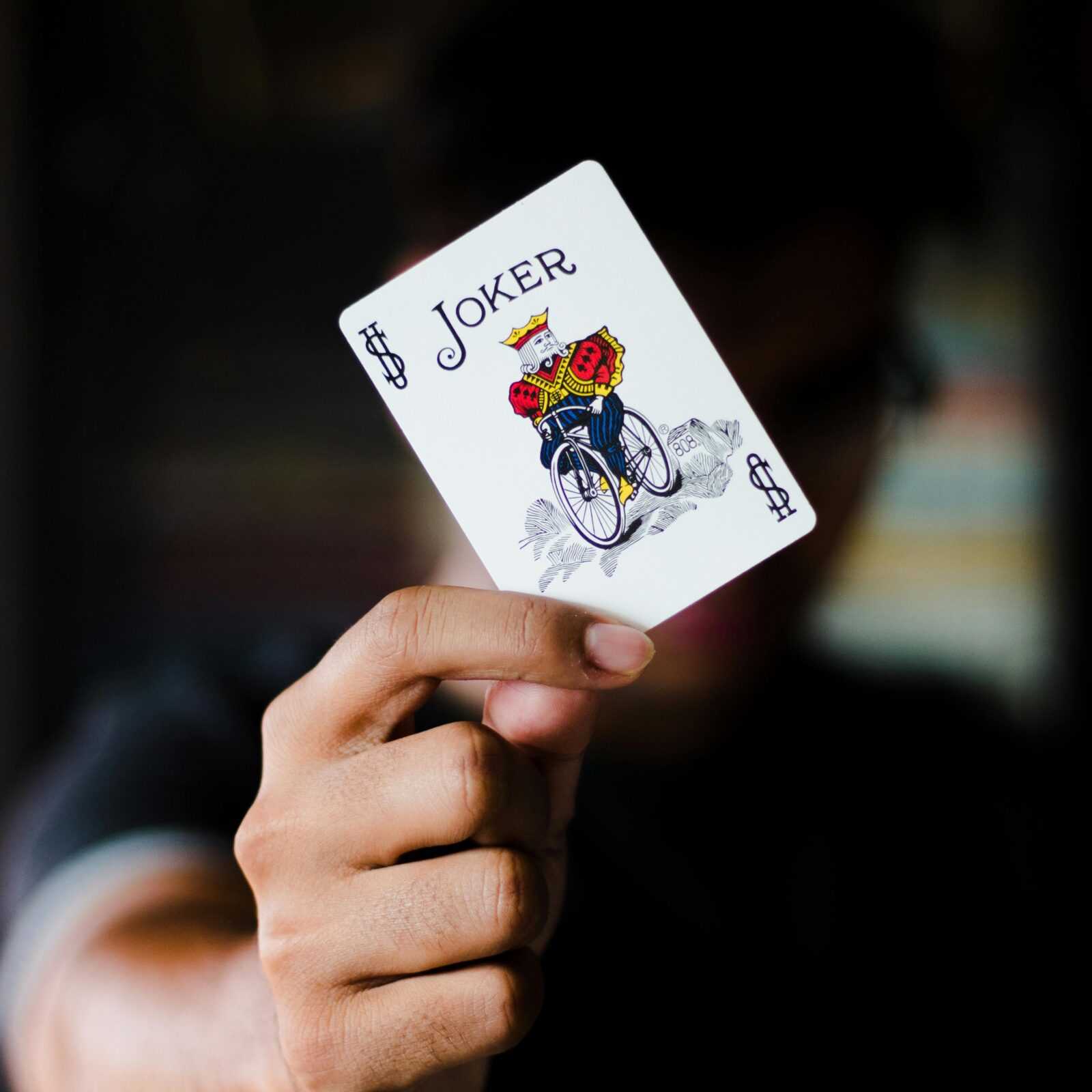 A focused shot of a person holding a Joker playing card, ideal for gambling themes.